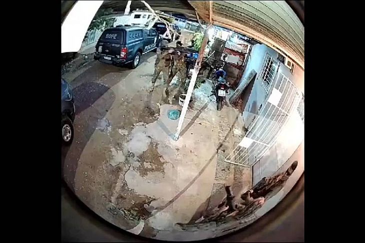 Imagem de câmera de segurança mostra momento em que policiais invadem imóvel; momentos depois, eles saem carregando um corpo em um lençol 