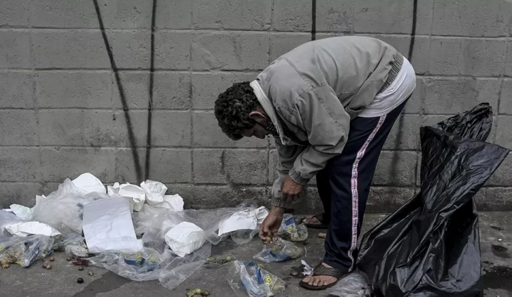 Morador procura resto de comida no lixo em São Paulo