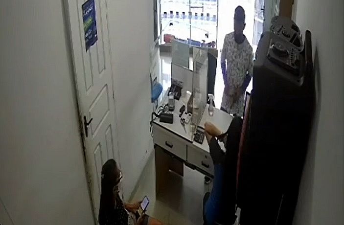 Assaltante mostra arma de fogo à funcionária de loja, que não reaje